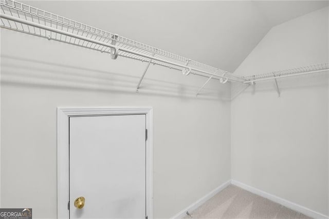 walk in closet featuring carpet floors and lofted ceiling