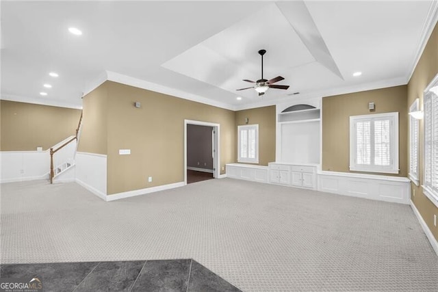 carpeted spare room with a tray ceiling, ceiling fan, and ornamental molding