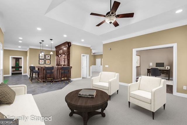 living room with ceiling fan, ornamental molding, carpet floors, and bar area