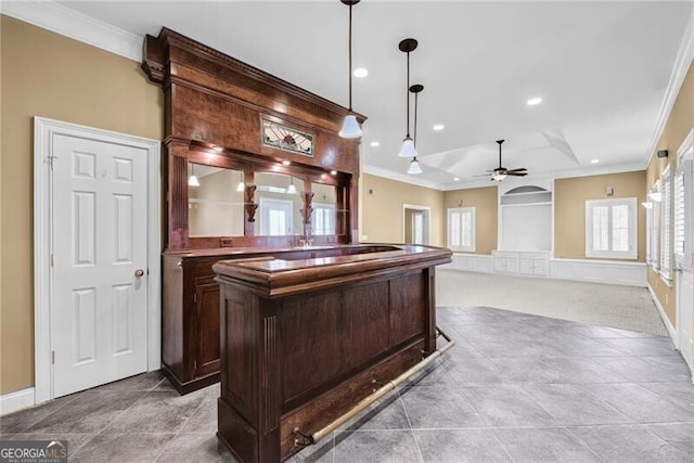 bar with hanging light fixtures, ceiling fan, ornamental molding, dark brown cabinets, and light colored carpet