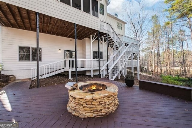 deck with a sunroom and an outdoor fire pit