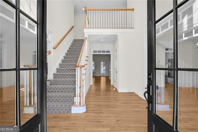 entryway with french doors, light wood-type flooring, crown molding, and a healthy amount of sunlight