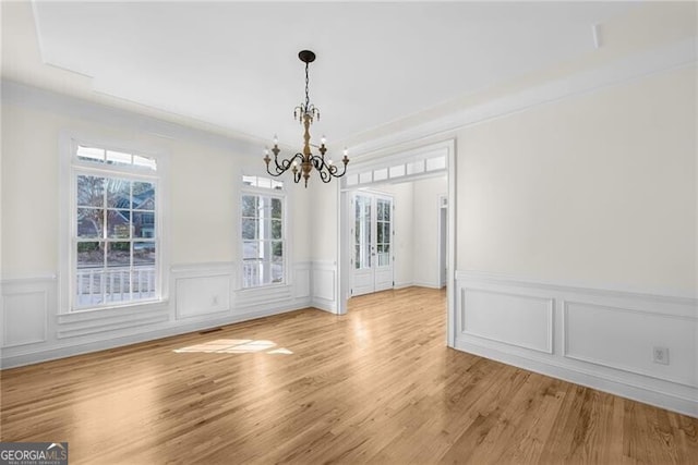 unfurnished dining area featuring light wood-type flooring and an inviting chandelier