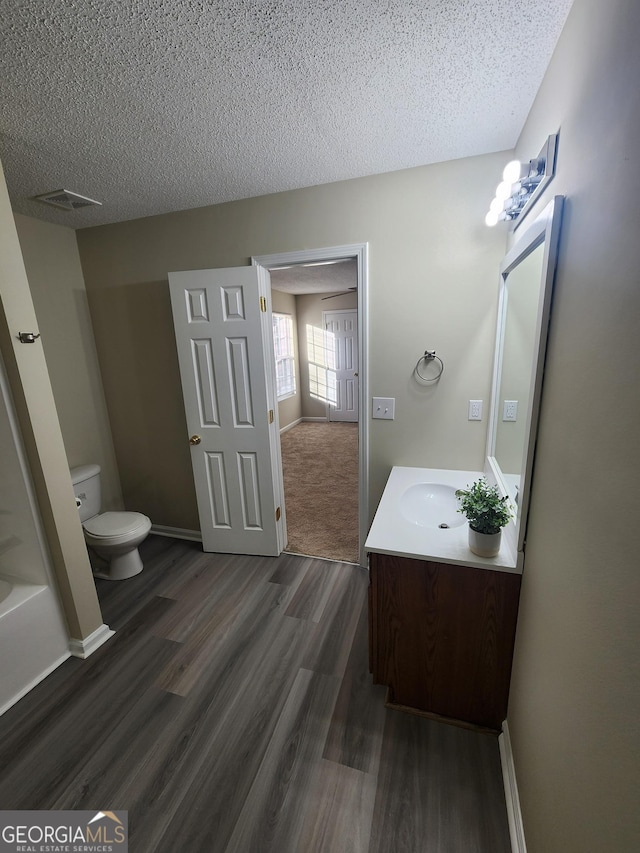 full bathroom featuring baseboards, toilet, wood finished floors, a textured ceiling, and vanity