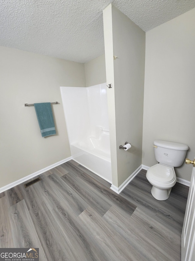 full bathroom featuring toilet, baseboards, visible vents, and wood finished floors