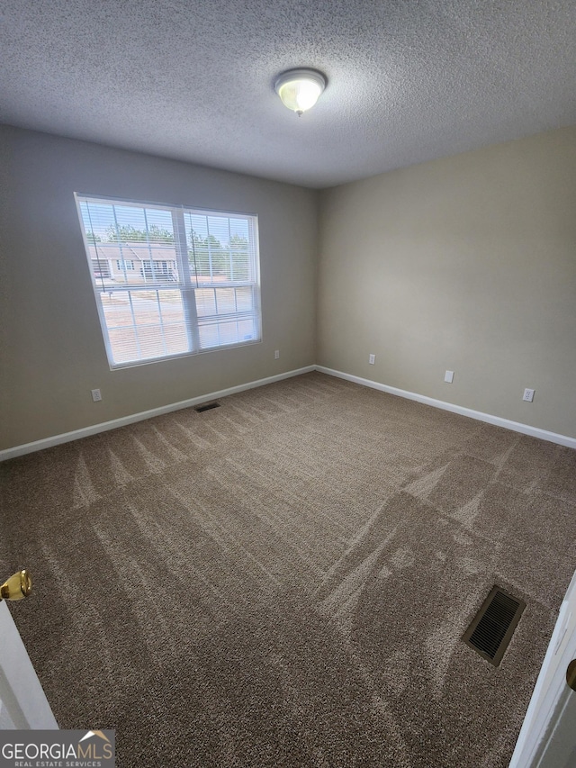 carpeted empty room featuring visible vents, a textured ceiling, and baseboards