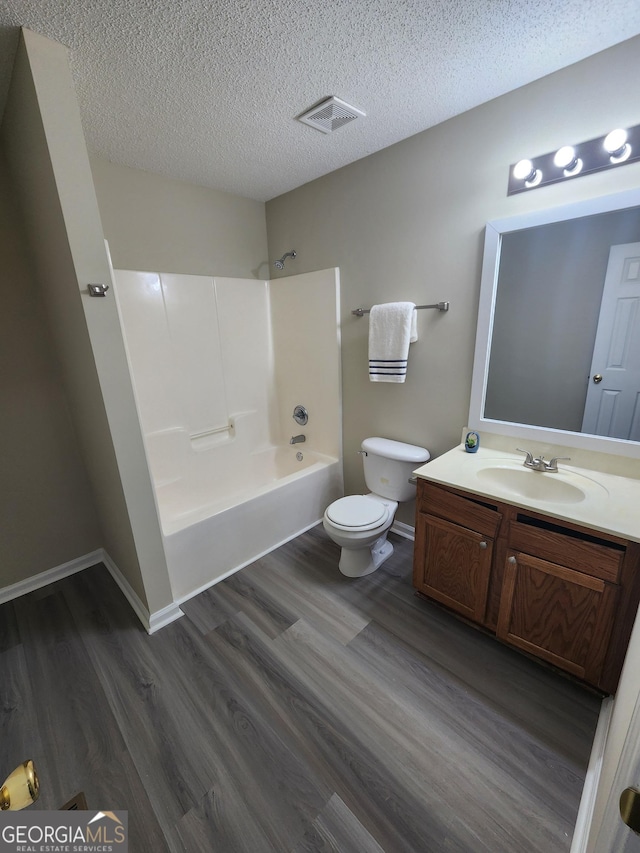 bathroom with visible vents, toilet, shower / tub combination, wood finished floors, and a textured ceiling