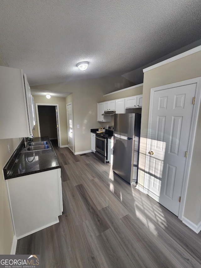 kitchen featuring stainless steel appliances, a sink, white cabinets, dark wood-style floors, and dark countertops