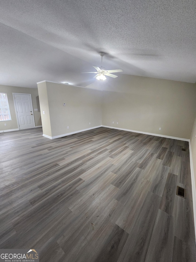 interior space featuring ceiling fan, a textured ceiling, dark wood-style flooring, visible vents, and baseboards