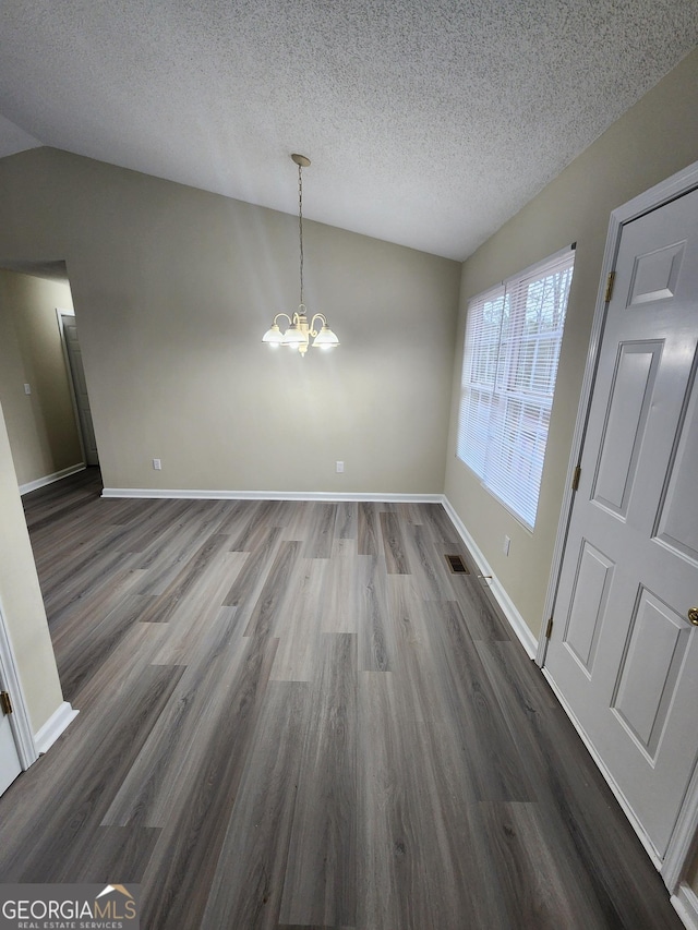 unfurnished dining area with lofted ceiling, dark wood-type flooring, baseboards, and a notable chandelier