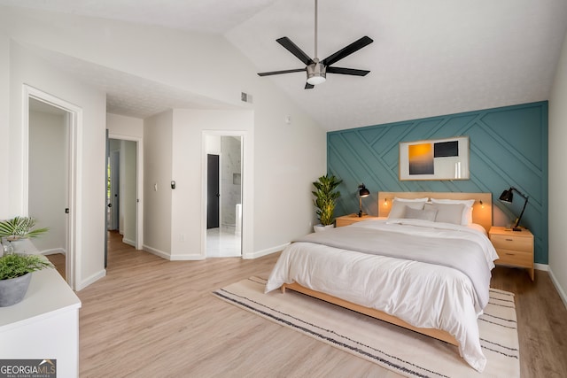 bedroom featuring ceiling fan, ensuite bathroom, lofted ceiling, and light hardwood / wood-style floors