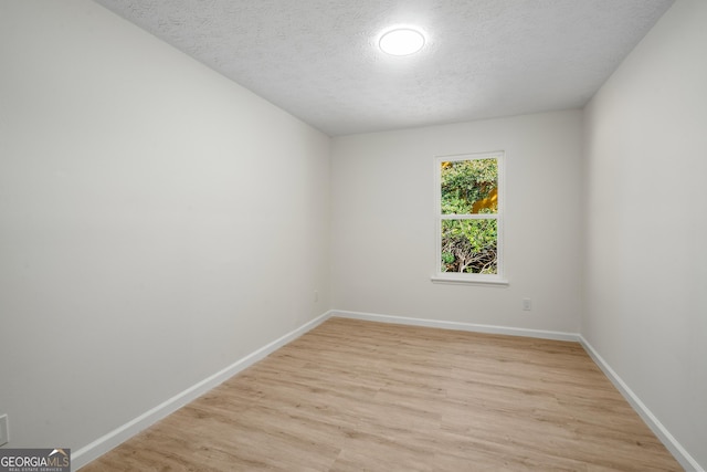 spare room featuring light hardwood / wood-style flooring and a textured ceiling