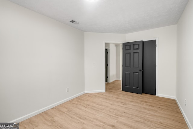 spare room featuring light wood-type flooring and a textured ceiling