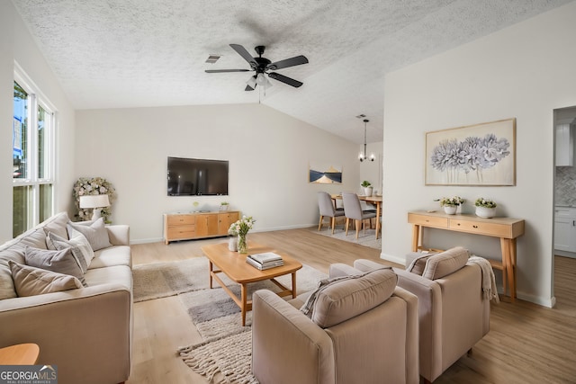 living room featuring vaulted ceiling, a textured ceiling, ceiling fan with notable chandelier, and light wood-type flooring