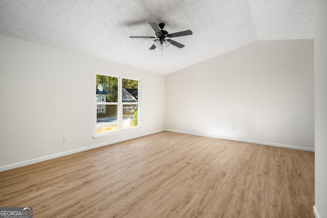 unfurnished room featuring a textured ceiling, light hardwood / wood-style floors, vaulted ceiling, and ceiling fan