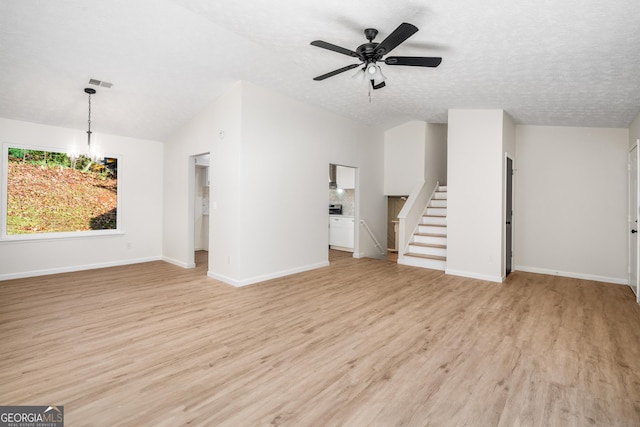 unfurnished living room with lofted ceiling, light hardwood / wood-style flooring, ceiling fan with notable chandelier, and a textured ceiling