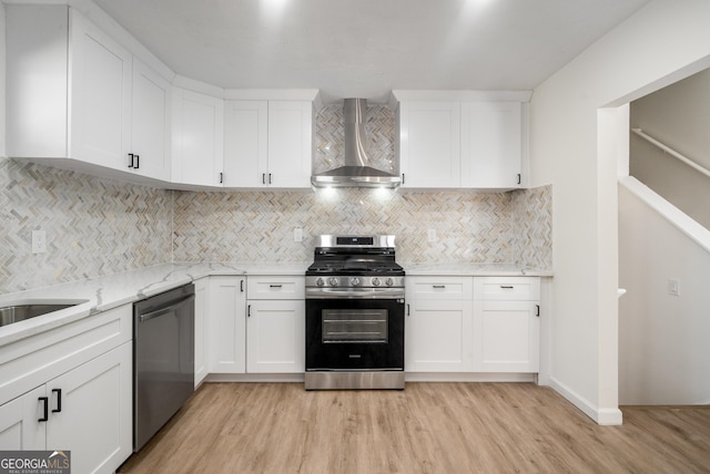 kitchen with wall chimney exhaust hood, decorative backsplash, white cabinetry, and stainless steel appliances