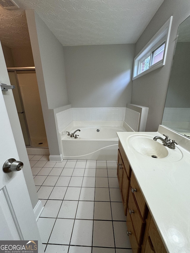 bathroom featuring plus walk in shower, a textured ceiling, vanity, and tile patterned floors