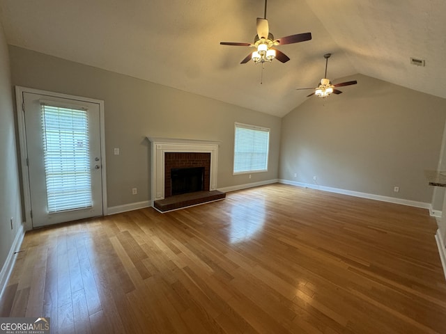 unfurnished living room with ceiling fan, wood-type flooring, a fireplace, and a wealth of natural light