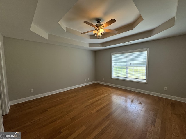 spare room featuring dark hardwood / wood-style flooring, a tray ceiling, and ceiling fan