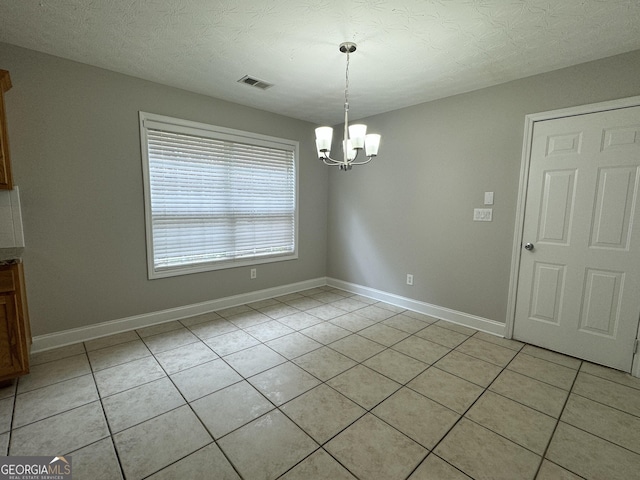 unfurnished dining area featuring light tile patterned flooring, a chandelier, and a textured ceiling