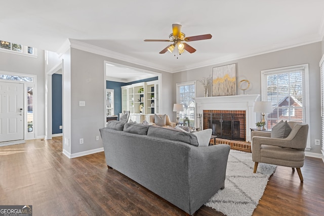 living room with ceiling fan, dark wood-type flooring, crown molding, and a brick fireplace