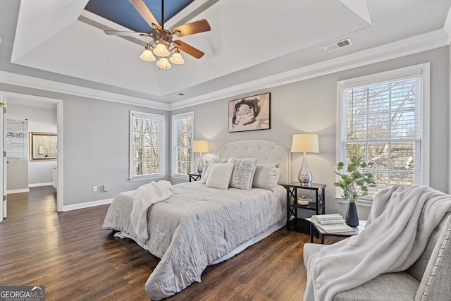 bedroom with a raised ceiling, ceiling fan, dark wood-type flooring, and multiple windows