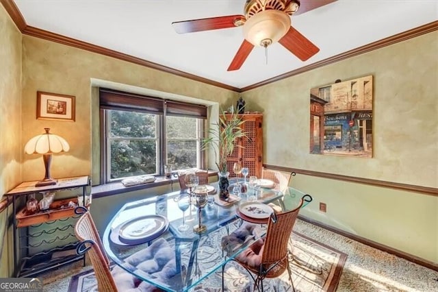 carpeted dining space with ceiling fan and crown molding