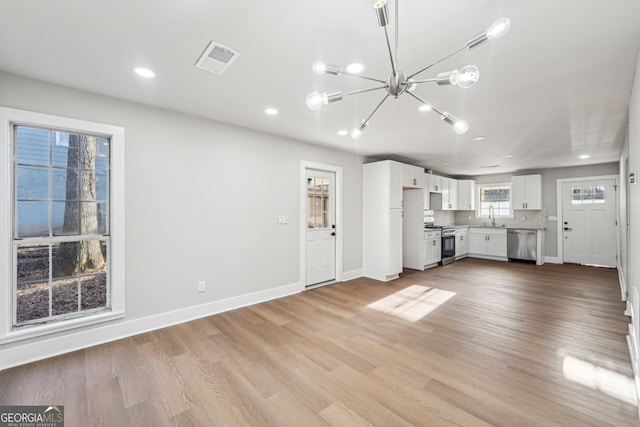 unfurnished living room featuring light wood-type flooring, a notable chandelier, and sink