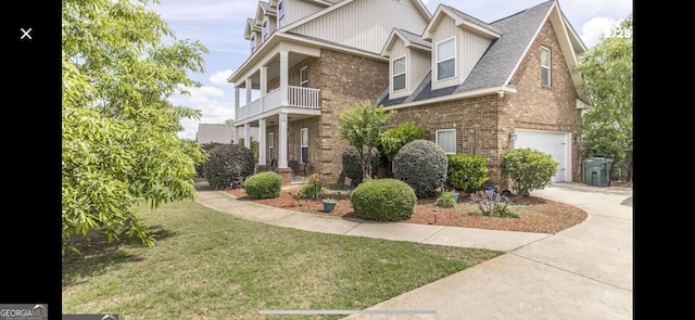 view of front of property featuring a balcony, a front lawn, and a garage