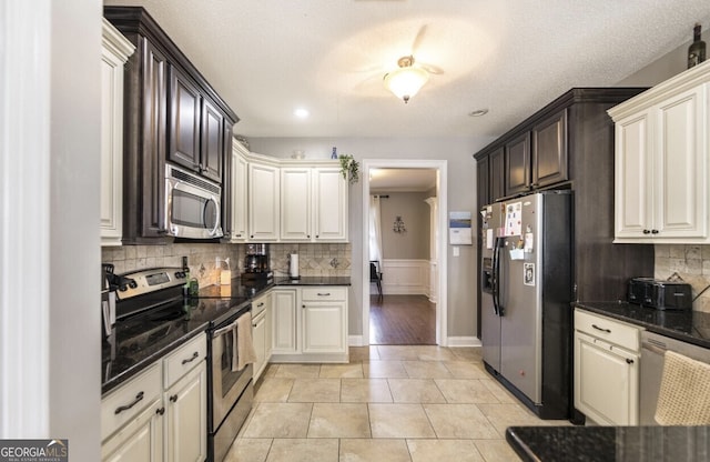 kitchen featuring a textured ceiling, stainless steel appliances, dark stone countertops, and light tile patterned flooring