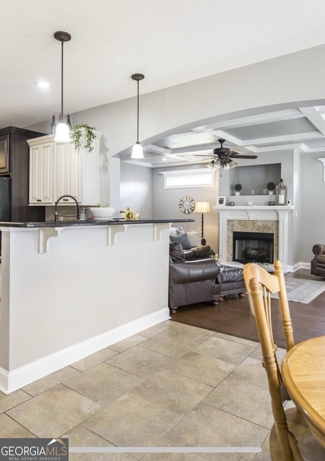 kitchen featuring ceiling fan, hanging light fixtures, a kitchen breakfast bar, kitchen peninsula, and a fireplace