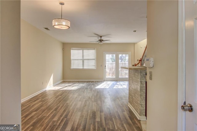 unfurnished living room featuring ceiling fan and dark wood-type flooring