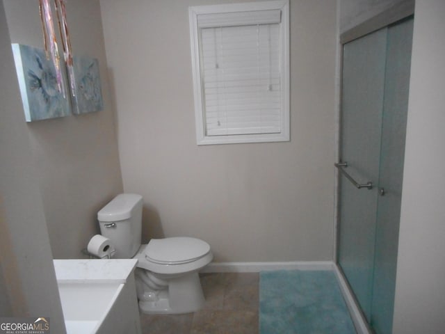 bathroom featuring vanity, a shower with door, tile patterned flooring, and toilet