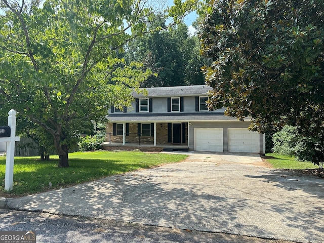 view of property featuring covered porch, a front yard, and a garage