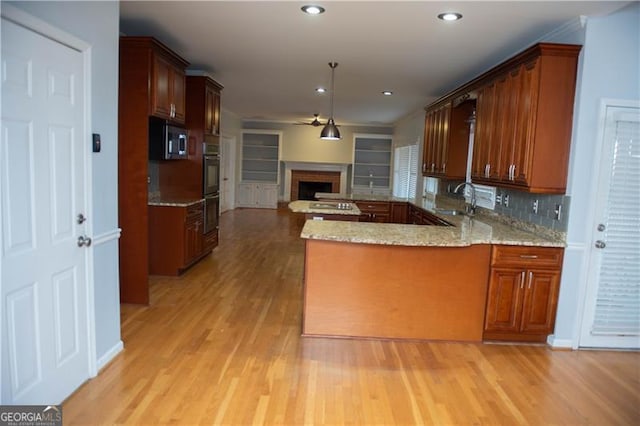 kitchen with kitchen peninsula, decorative backsplash, appliances with stainless steel finishes, light hardwood / wood-style flooring, and a fireplace