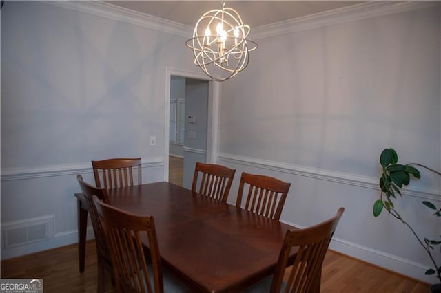 dining area with hardwood / wood-style flooring, a chandelier, and ornamental molding