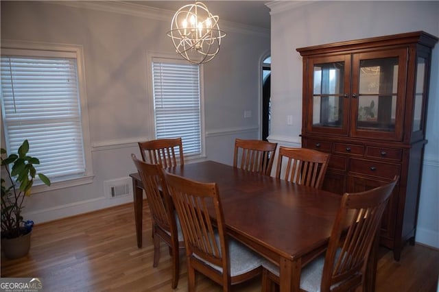 dining room with hardwood / wood-style floors, an inviting chandelier, and ornamental molding