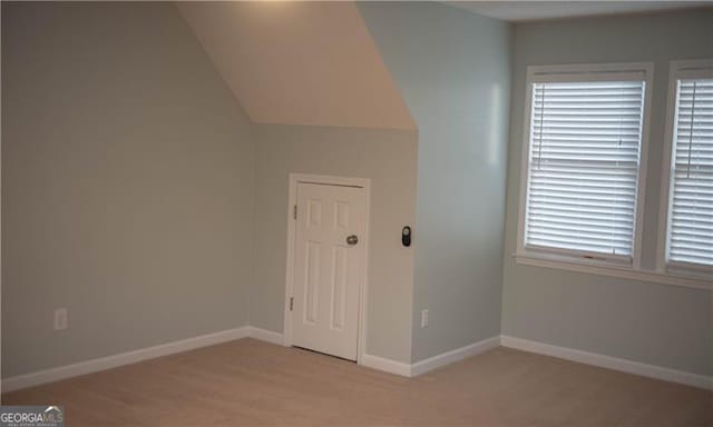 additional living space featuring light carpet and vaulted ceiling