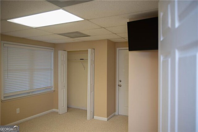 interior space featuring a paneled ceiling, a closet, and light colored carpet