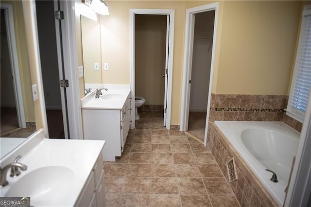 bathroom with vanity, toilet, and tiled tub