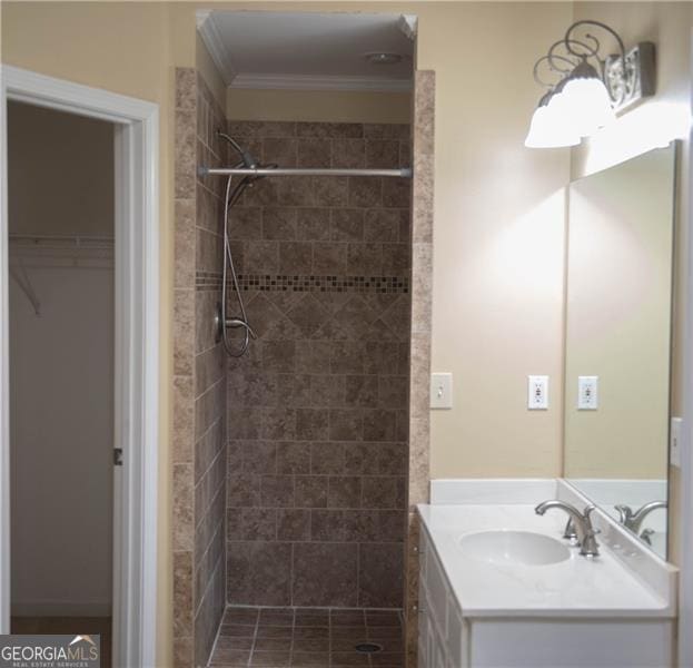 bathroom featuring a tile shower, crown molding, and vanity