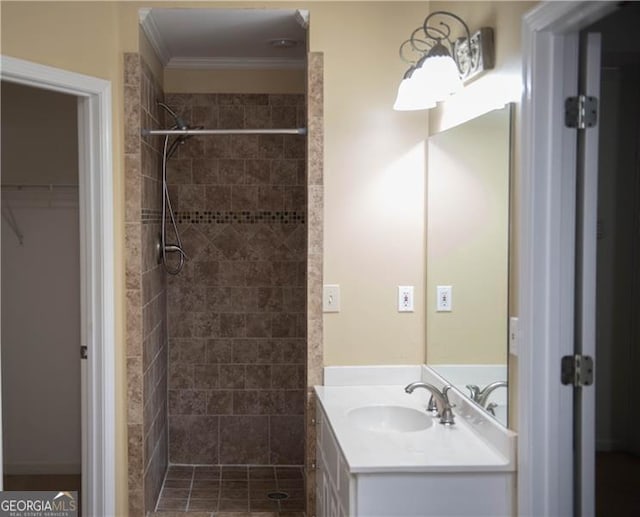 bathroom with tiled shower, vanity, and ornamental molding