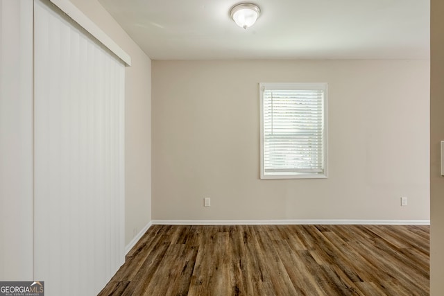 unfurnished room with dark wood-type flooring