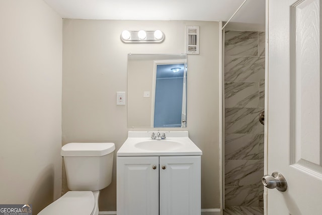 bathroom with toilet, vanity, and tiled shower