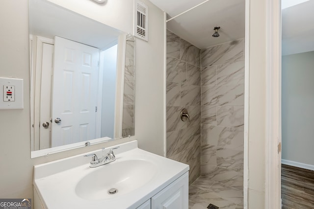 bathroom featuring a tile shower and vanity