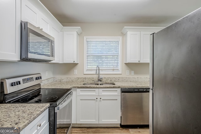 kitchen featuring sink, white cabinetry, light stone counters, and appliances with stainless steel finishes