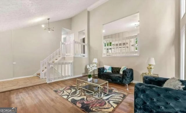 living room featuring hardwood / wood-style floors, lofted ceiling, and a notable chandelier