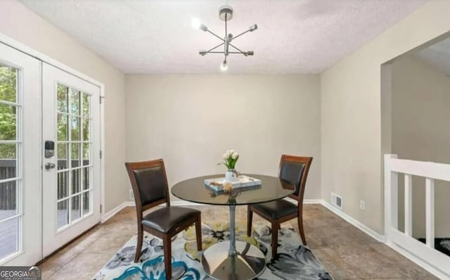 dining room featuring french doors, a textured ceiling, and a notable chandelier