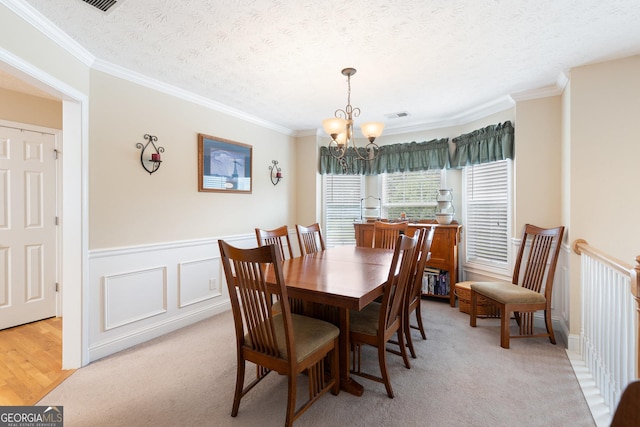 dining room with crown molding, light colored carpet, a textured ceiling, and an inviting chandelier